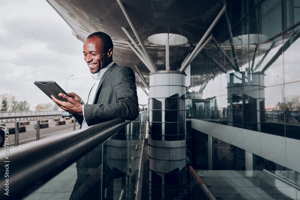 Found it amusing. Waist up portrait of businessperson near terminal looking at gadget and smiling Found it amusing. Waist up portrait of businessperson near terminal looking at gadget and smiling
