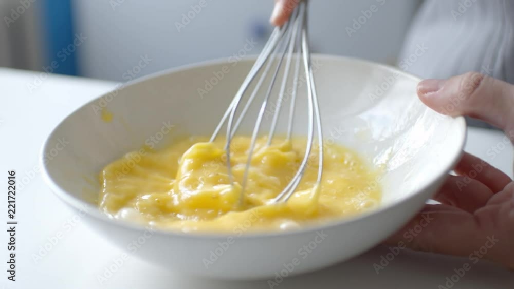 Slow motion crop shot of woman preparing homemade omelette mixing with whisk eggs. Slow motion crop shot of woman preparing homemade omelette mixing with whisk eggs.