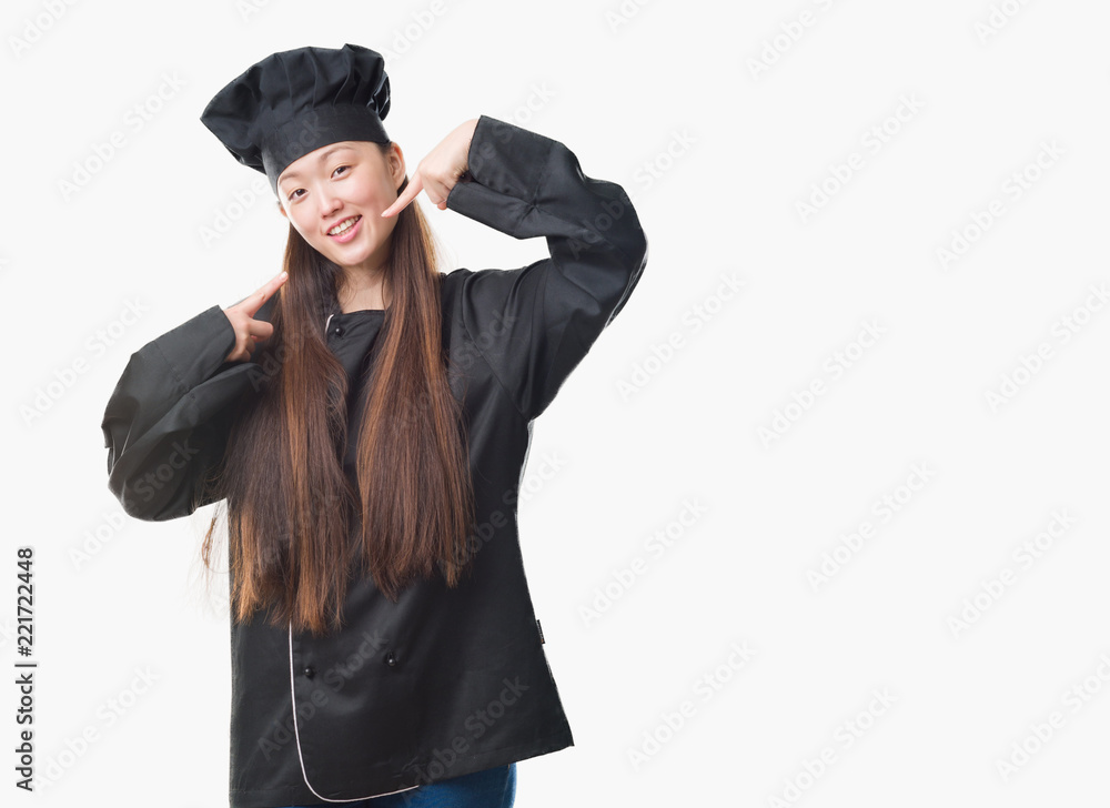 Young Chinese woman over isolated background wearing chef uniform smiling confident showing and pointing with fingers teeth and mouth. Health concept. Young Chinese woman over isolated background wearing chef uniform smiling confident showing and pointing with fingers teeth and mouth. Health concept.