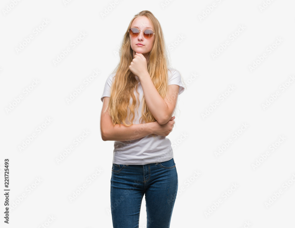 Blonde teenager woman wearing sunglasses serious face thinking about question, very confused idea Blonde teenager woman wearing sunglasses serious face thinking about question, very confused idea