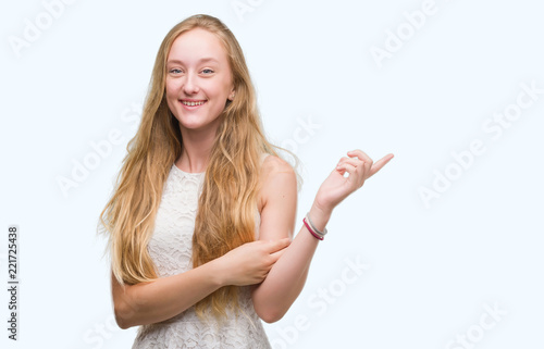 Blonde teenager woman very happy pointing with hand and finger to the side © Krakenimages.com