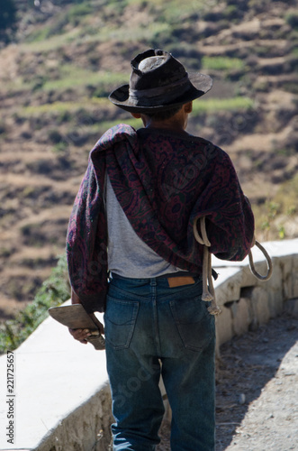 Close-up of old farmer with hat walking with a knife at the edge of the cliff by a mountain