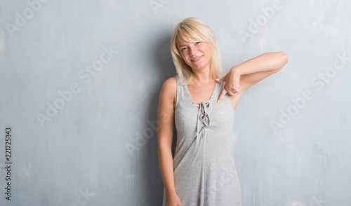 Adult caucasian woman over grunge grey wall wearing a dress with surprise face pointing finger to himself © Krakenimages.com
