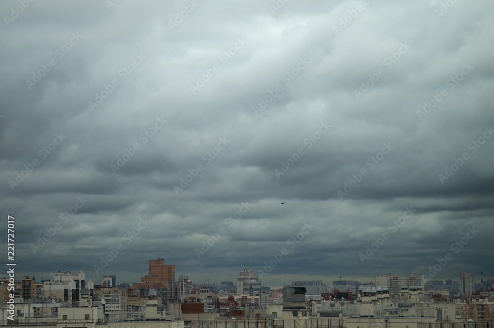 Aerial view on roofs and windows of residential high-rises of the big city under a gray cloudy sky