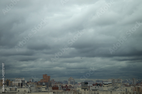 Aerial view on roofs and windows of residential high-rises of the big city under a gray cloudy sky