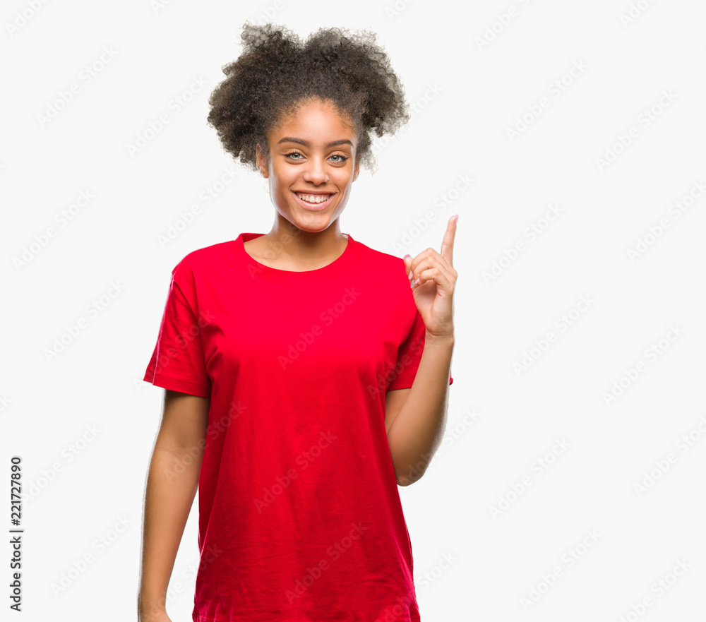 Young afro american woman over isolated background showing and pointing up with finger number one while smiling confident and happy. Young afro american woman over isolated background showing and pointing up with finger number one while smiling confident and happy.