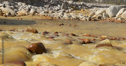 Yellow River, Chilecito. Detail of 4x4 van's wheels crossing the river. Splashing water. Close detail of water flowing along rocky basin. Camera stays still. Rocks at background.La Rioja, Argentina. photo