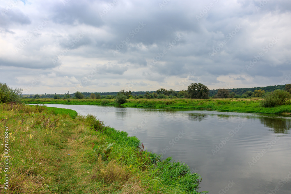View of river surface on a background of sky with gray clouds. River landscape on a autumn day