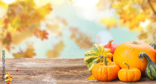 pile of orange raw pumpkins with fall leaves on wooden table over fall background photo