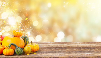 pile of orange harvest pumpkins with fall leaves on wooden table over fall background banner