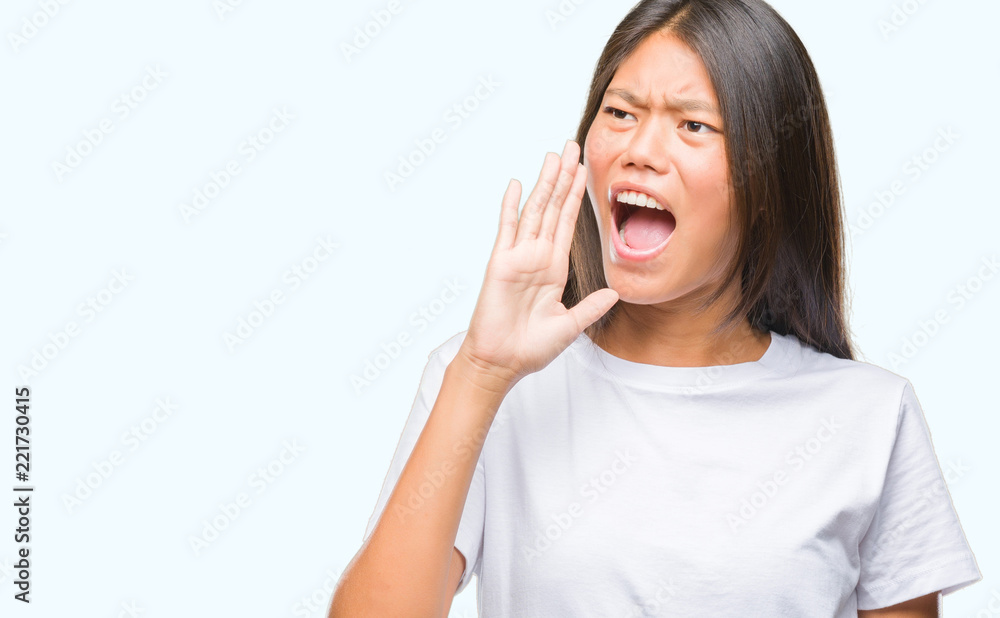 Young asian woman over isolated background shouting and screaming loud to side with hand on mouth. Communication concept. Young asian woman over isolated background shouting and screaming loud to side with hand on mouth. Communication concept.