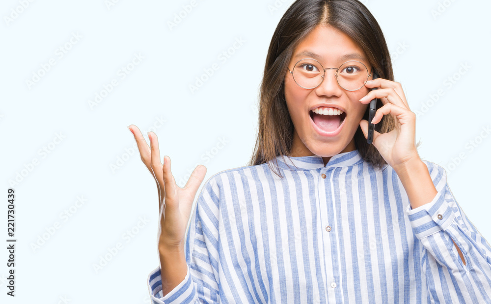 Young asian woman speaking on the phone over isolated background very happy and excited, winner expression celebrating victory screaming with big smile and raised hands Young asian woman speaking on the phone over isolated background very happy and excited, winner expression celebrating victory screaming with big smile and raised hands