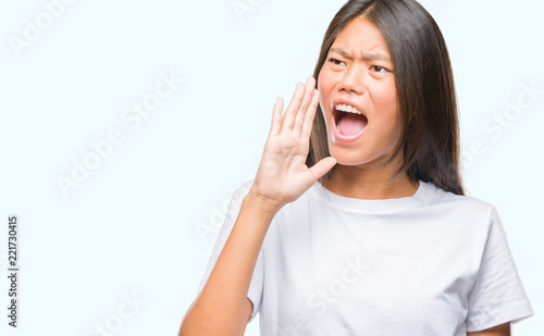 Young asian woman over isolated background shouting and screaming loud to side with hand on mouth. Communication concept.