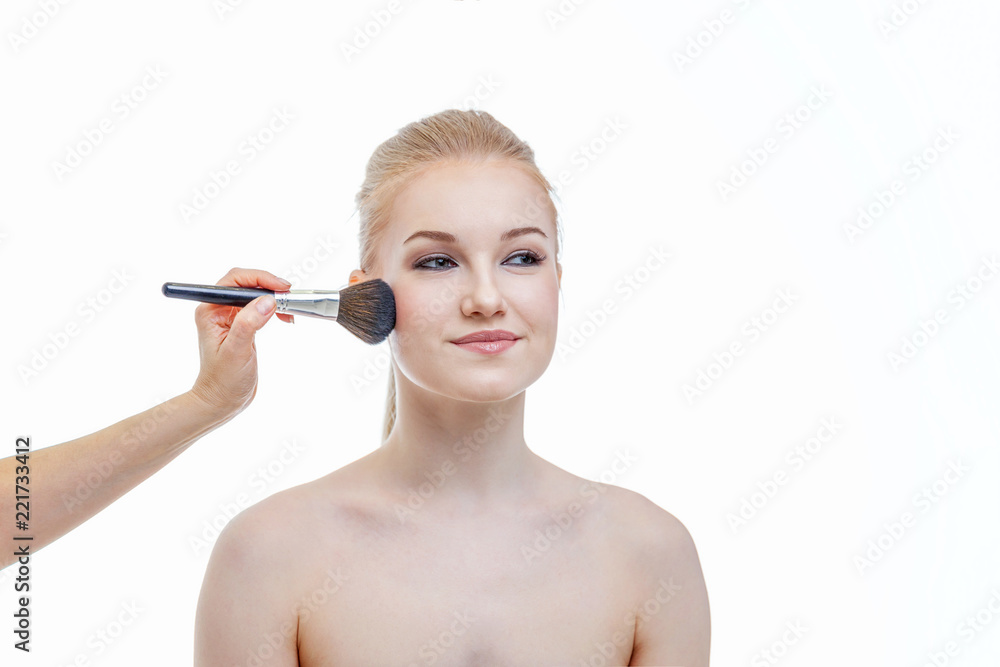 Hand of makeup master applying powder for young woman model on white background. Professional make up applying by artist. Beautiful girl face with perfect skin. Make-up detail in process Hand of makeup master applying powder for young woman model on white background. Professional make up applying by artist. Beautiful girl face with perfect skin. Make-up detail in process