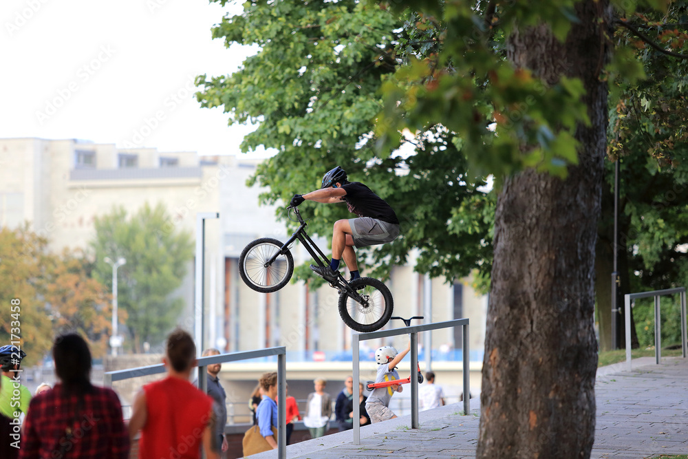 Młody mężczyzna skacze na rowerze przez barierkę na Wrocławskim bulwarze. - obrazy, fototapety, plakaty 