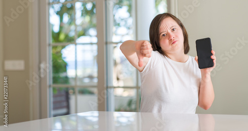 Down syndrome woman at home using smartphone with angry face, negative sign showing dislike with thumbs down, rejection concept Free Download Down syndrome woman at home using smartphone with angry face, negative sign showing dislike with thumbs down, rejection concept - GFXLoad