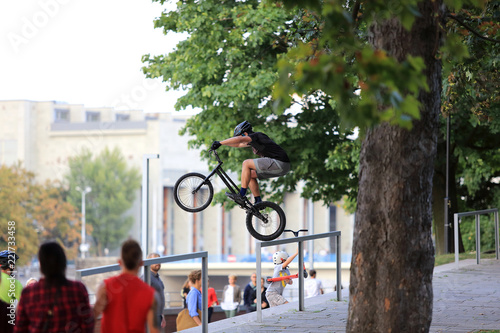 Młody mężczyzna skacze na rowerze przez barierkę na Wrocławskim bulwarze.