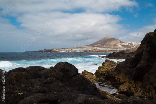 Sea landscape on the coast of Gran Canaria. Galdar. Blue sky with clouds, mountains and colorful houses.