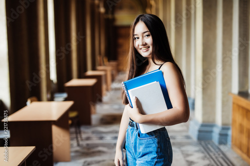 Fotografie Young asian girl university student with notebooks inside campus building