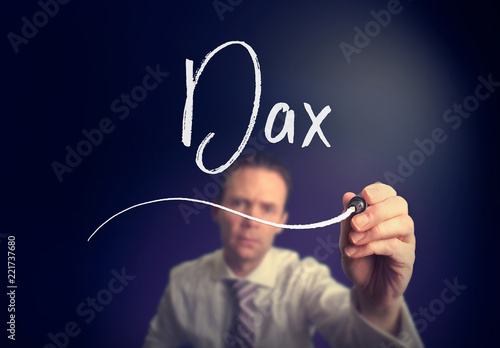 A businessman writing a DAX concept with a white pen on a clear screen.