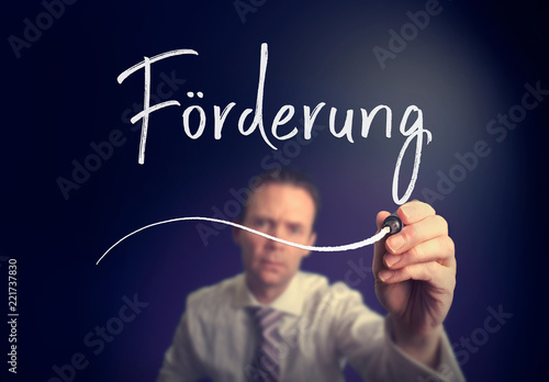 A businessman writing a Promotion "Förderung" concept in German with a white pen on a clear screen.