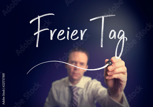 A businessman writing a Day Off "Freier Tag" concept in German with a white pen on a clear screen.