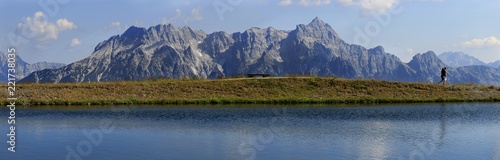 Wide Panorama of the mountains in the Alps with people enjoying the hike and lake in the foreground