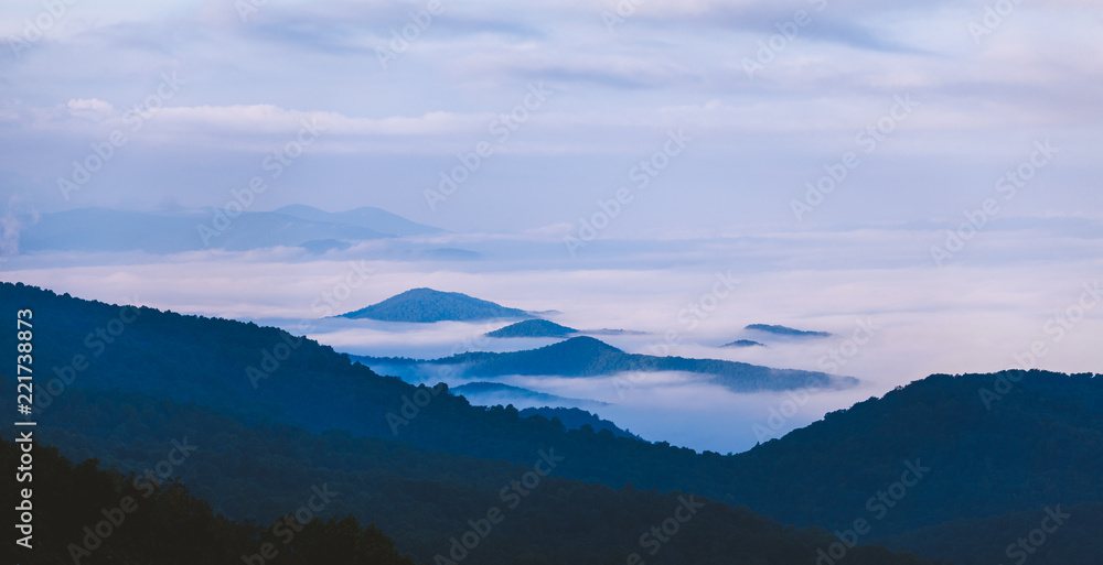 Naklejka premium Fog settles between mountains in Shenandoah National Park, VA on a foggy morning.