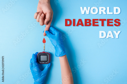 inscription world diabetes day, Nurse making a blood test. Man's hand with red blood drop and Glucose meter