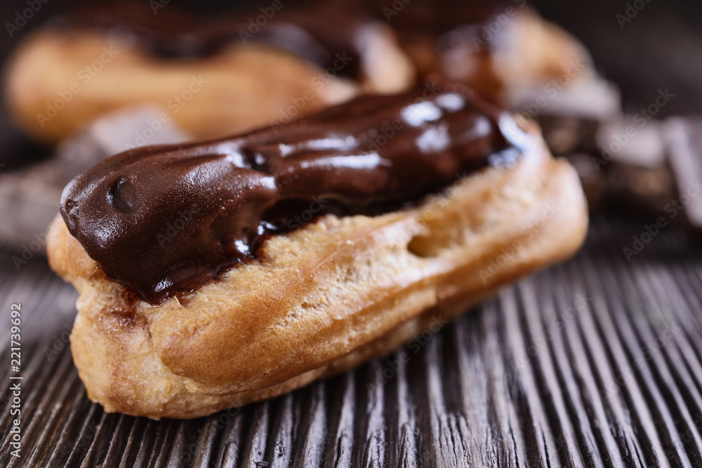 Cakes eclairs decorated with chocolate cream on top of are on a wooden table	