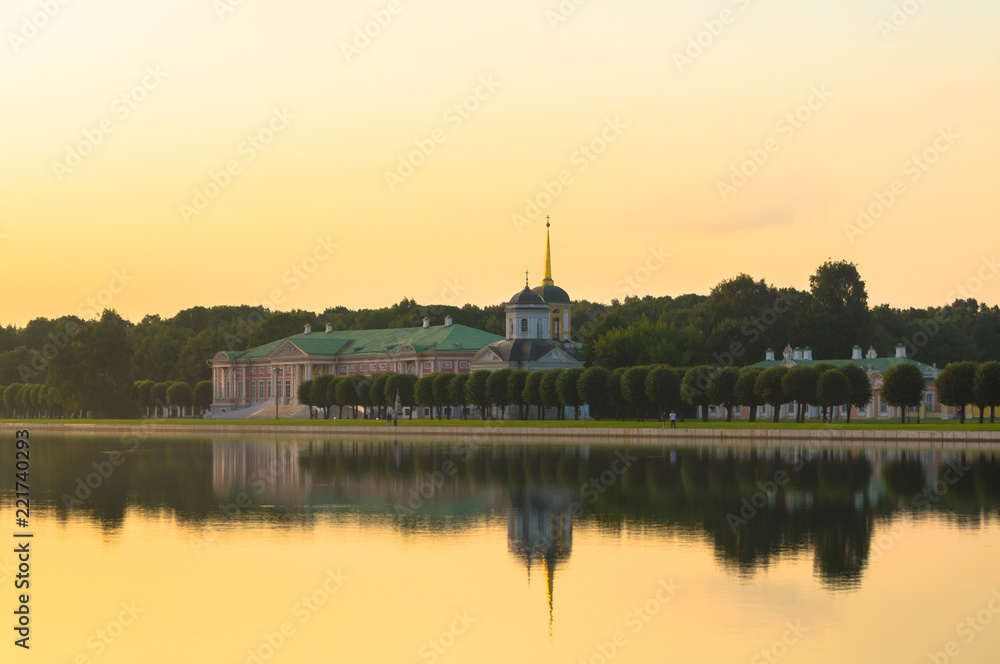Summer sunset on the palace pond of museum-estate Kuskovo, Moscow. Russia. Mysterious moment when the orange sun says goodbye to nature. Its last reflection trembles on the water. .
