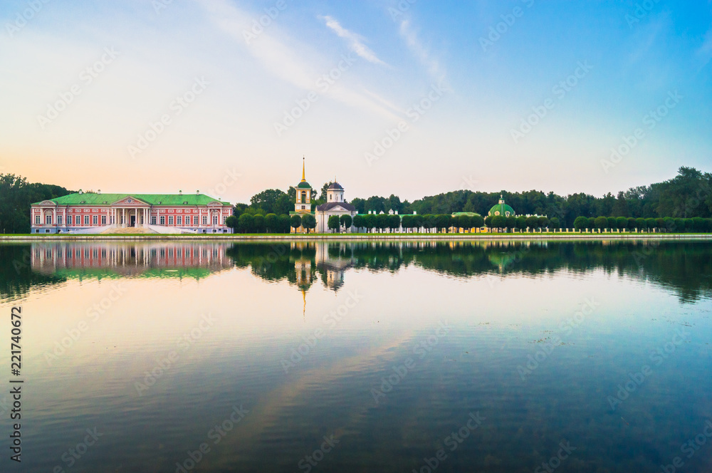 Glossy mirror surface of palace pond in the sunset light. Ensemble of the State reserve museum Kuskovo, former aristocratic summer country estate of the 18th century. Moscow. Russia.