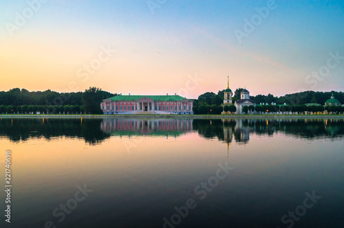 Glossy mirror surface of palace pond in the sunset light. Ensemble of the State reserve museum Kuskovo, former aristocratic summer country estate of the 18th century. Moscow. Russia.