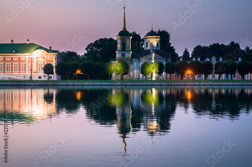 Glossy mirror surface of palace pond in the sunset light. Ensemble of the State reserve museum Kuskovo, former aristocratic summer country estate of the 18th century. Moscow. Russia.