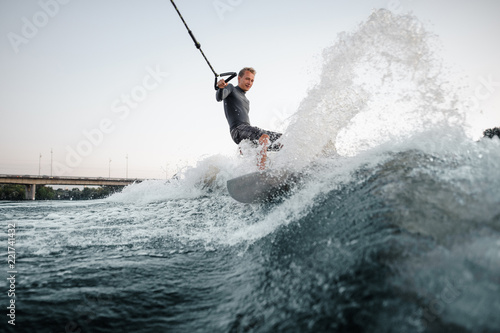 Happy man wakesurfing on the board down the blue water © fesenko