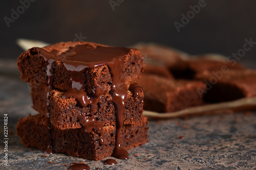 Brownie is a classic American dessert. Pie with chocolate sauce on a dark background.