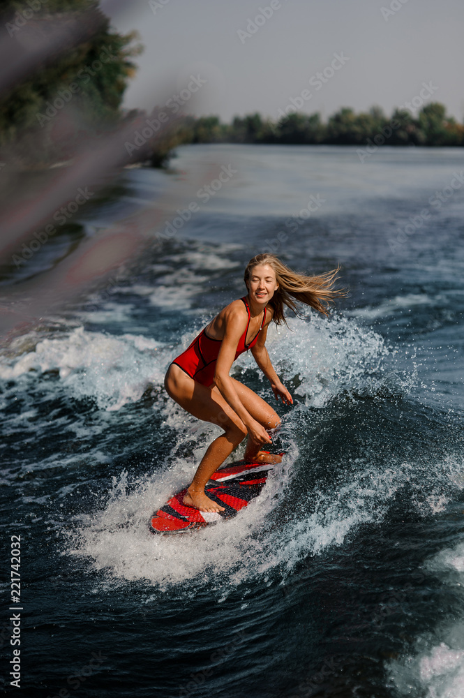 Fototapeta premium Sexy blonde woman wakesurfing on board down the blue water