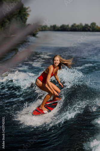 Sexy blonde woman wakesurfing on board down the blue water