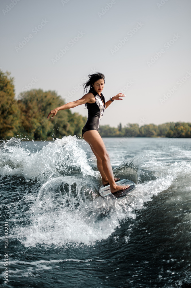 Sexy brunette woman wakesurfing on board down the blue water