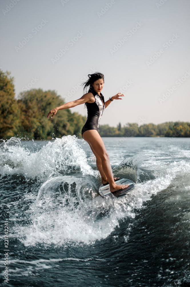 Sexy brunette woman wakesurfing on board down the blue water Sexy brunette woman wakesurfing on board down the blue water
