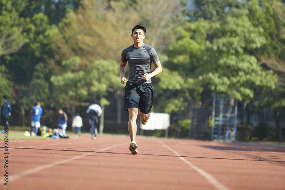 young asian male athlete running on track