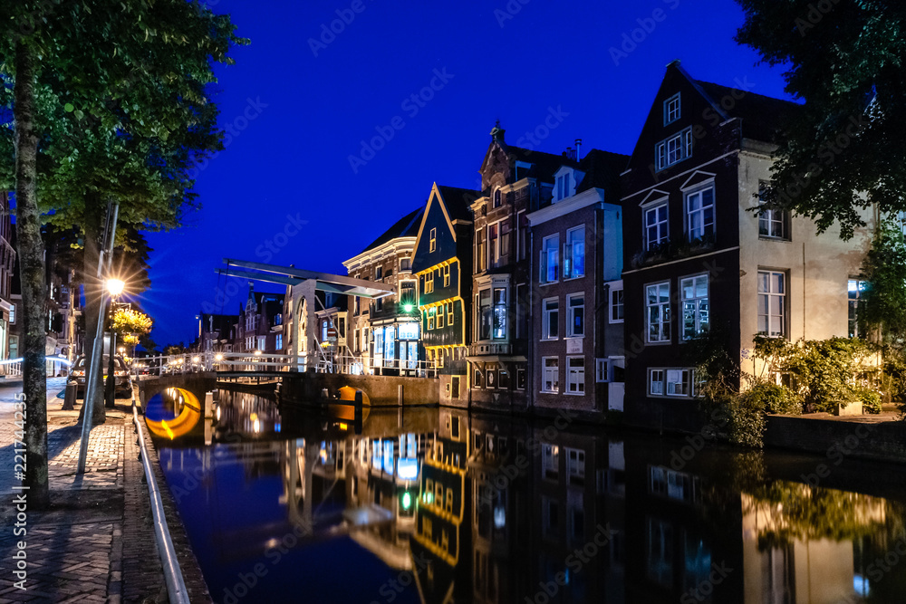 The illuminated monumental medieval houses and facades in the inner city of an Authentic Dutch old city center in Holland
