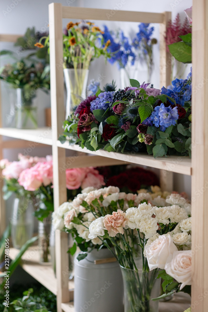 Fototapeta premium Flower shop concept. Different varieties fresh spring flowers in refrigerator room for flowers. Bouquets on shelf, florist business.
