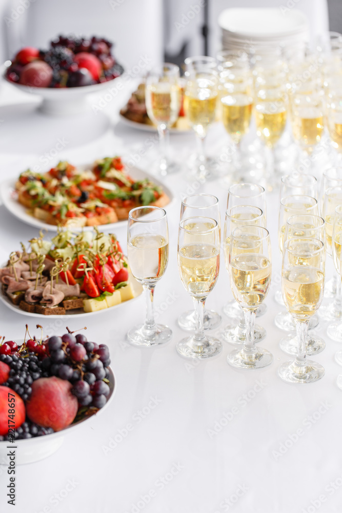 solemn happy new year banquet. Lot of glasses champagne or wine on the table in restaurant. buffet table with lots of delicious snacks. canapes, bruschetta, and little desserts on white plate solemn happy new year banquet. Lot of glasses champagne or wine on the table in restaurant. buffet table with lots of delicious snacks. canapes, bruschetta, and little desserts on white plate