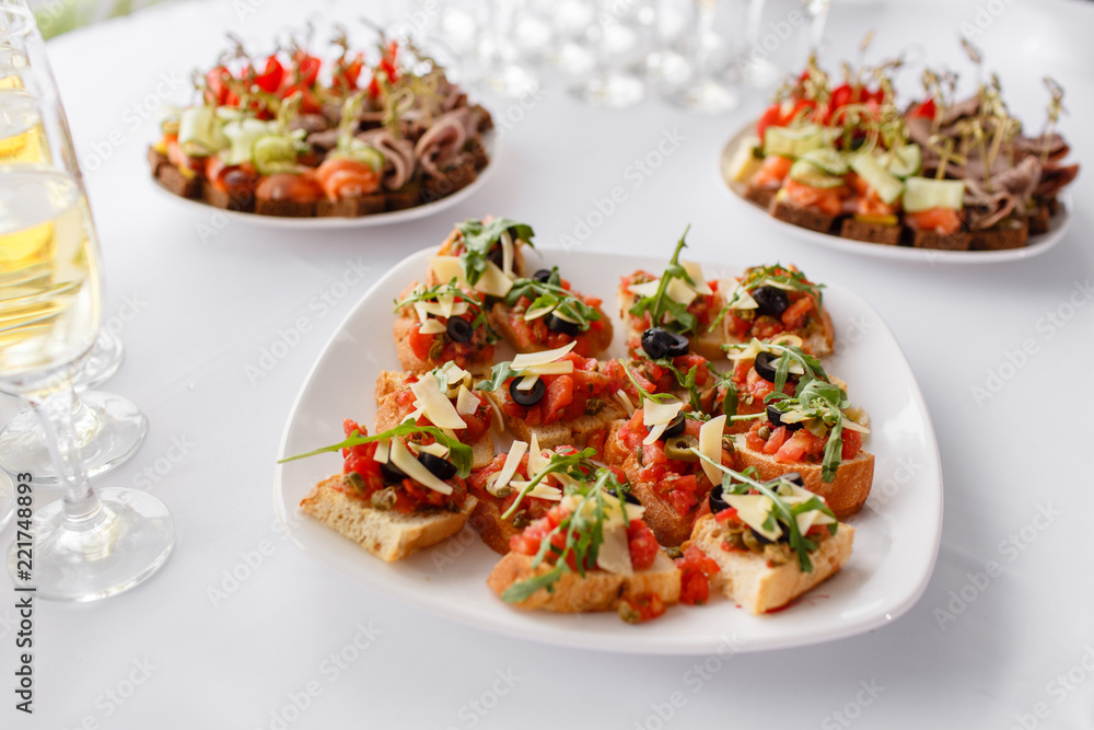 Plate with Italian appetizers. Bruschetta with a cherry tomatoes and shrimps. Parmesan cheese, olives, sun-dried tomatoes and walnuts. Plate with Italian appetizers. Bruschetta with a cherry tomatoes and shrimps. Parmesan cheese, olives, sun-dried tomatoes and walnuts.