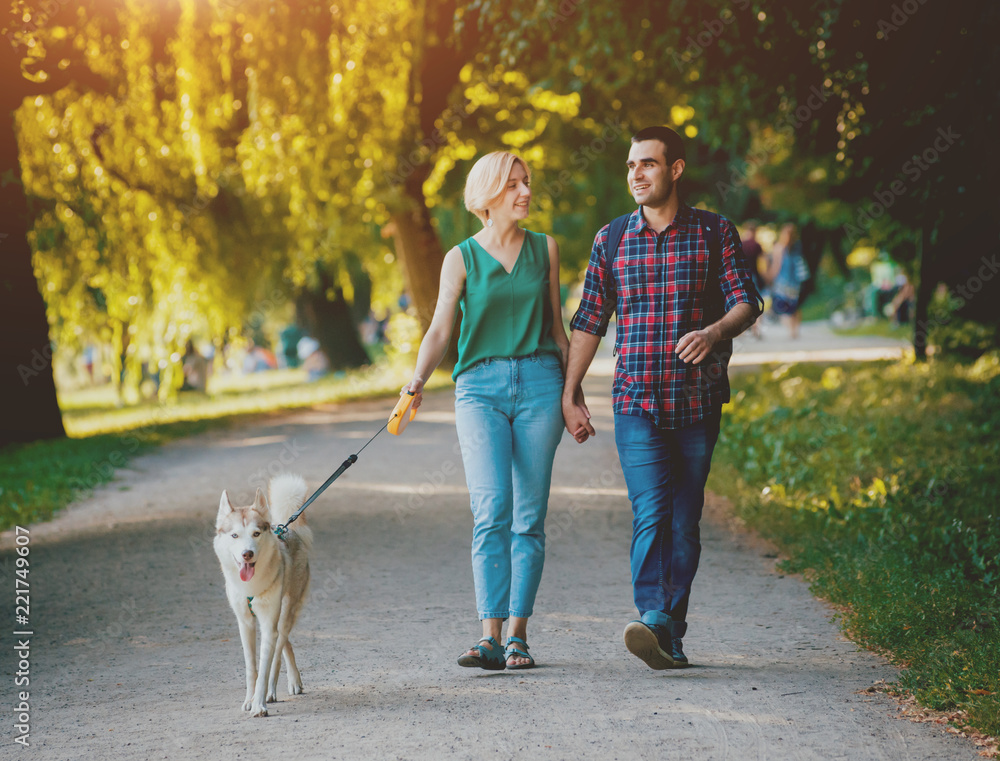 Dog with owners spend a day at the park. Young couple and husky running, playing and having fun. Dog with owners spend a day at the park. Young couple and husky running, playing and having fun.