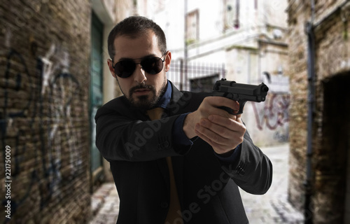 Mafia man or racketeer holds pistol in hands.