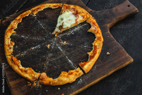 Tableau sur toile Last piece of delicious pizza on the wooden board