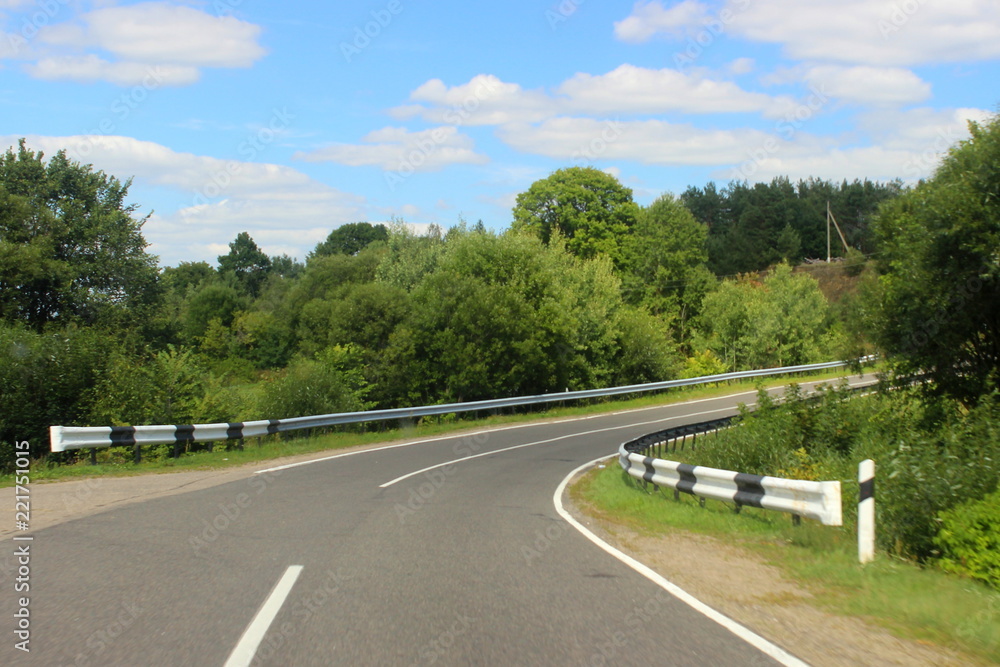 View from windshield on sphalt road turn in the perspective among the green trees on the roadsides and clear blue sky in summer day – travel, tourism, country landscape