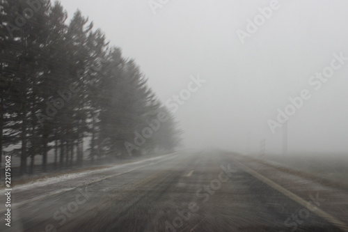 Snowstorm, view from windshield on first snow - european two way country asphalt road with limited visibility, difficult car driving, emergency, country landscape